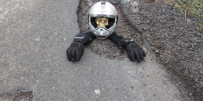 Csontvázzal és játékokkal tüntetett a motoros a kátyú ellen
