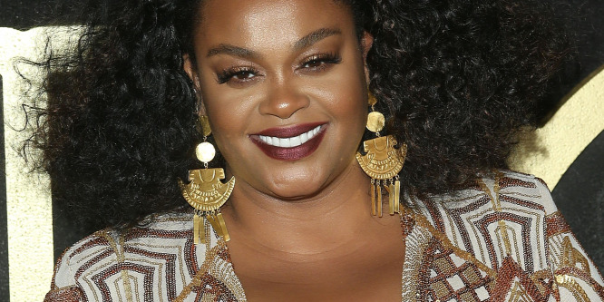 Jill Scott soulénekesn egy mikrofonnal mutatja be, hogyan elégíti ki a pasiját (18+)